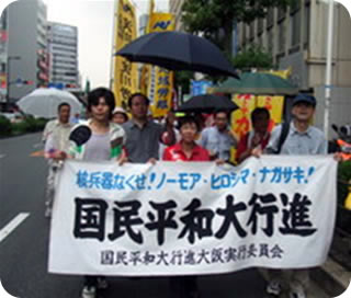淀川区役所を出発して雨の中を行進する参加者